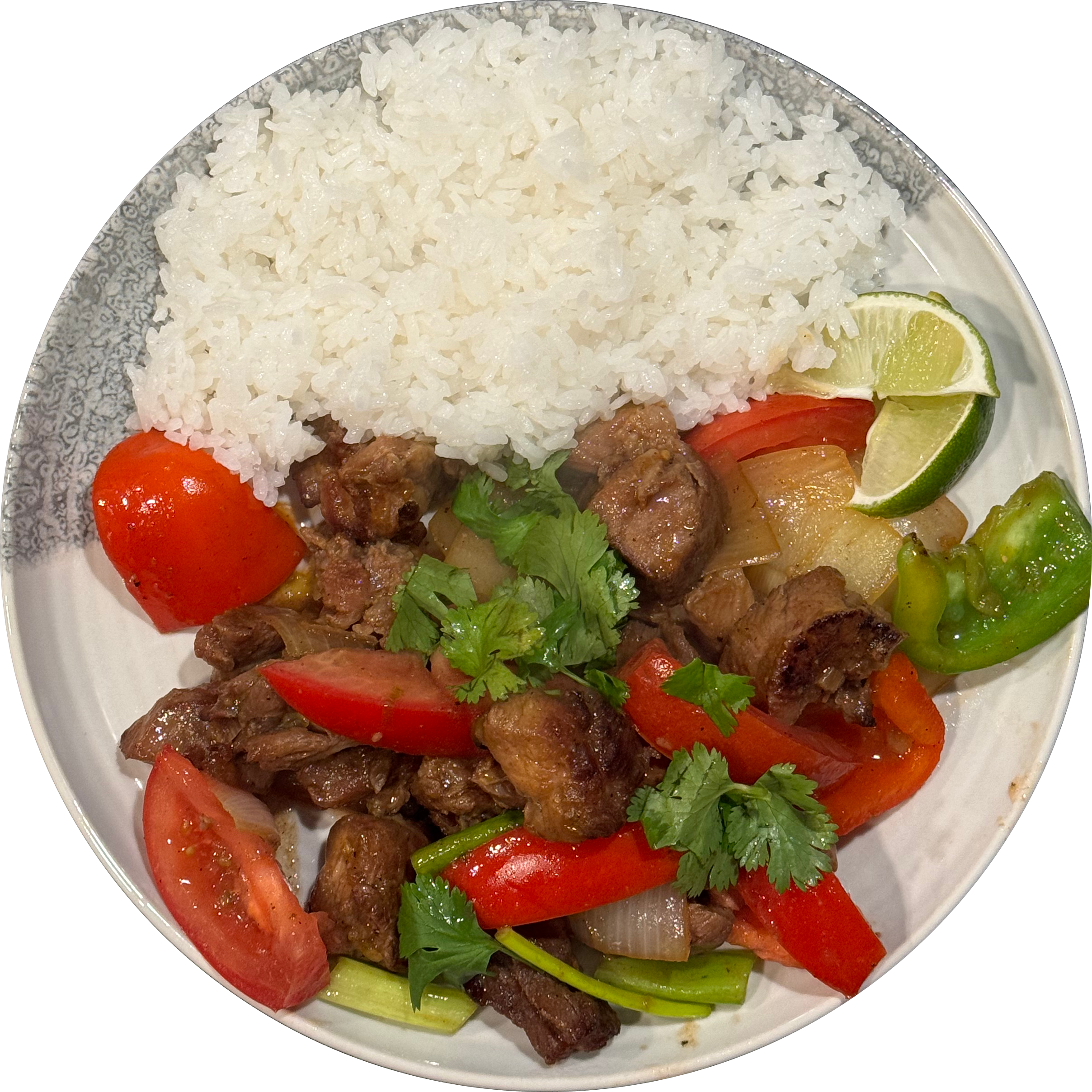 A photo of a plate with white rice and bo luc lac, a dish with pieces of pan fried pork, green bell pepper, tomato, cilantro, and lime.